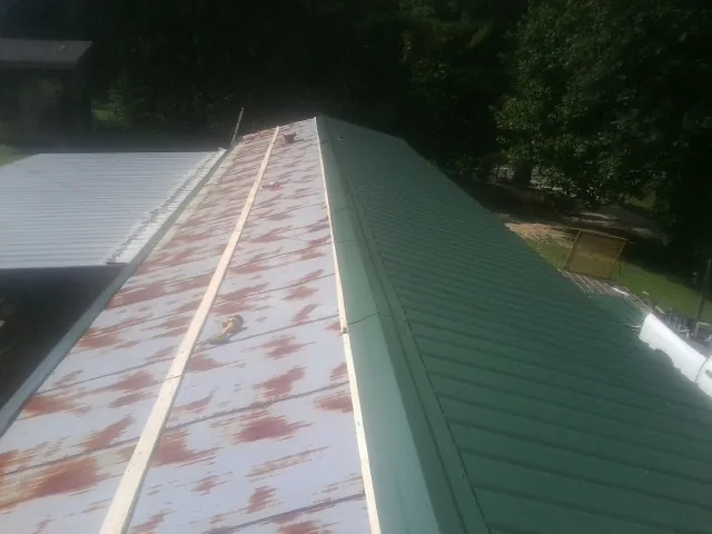 Old rusted panels beside newly installed green metal roofing — Wind Damage Roof Repair by Roofing Brothers in Zanesville