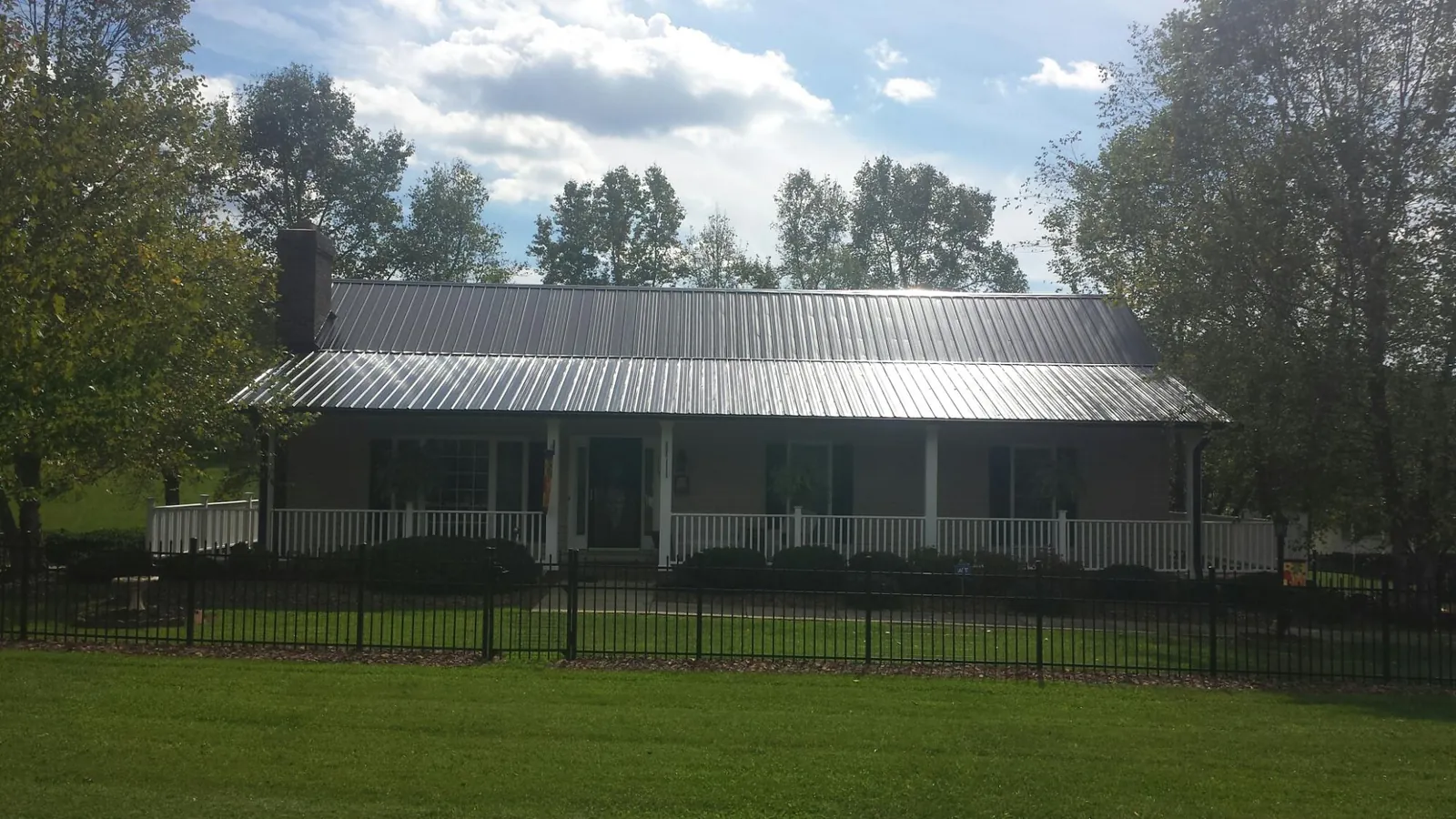 Gray metal roof on a brick ranch with a full width front porch — Gutter Guard Installation work by our crew in Zanesville