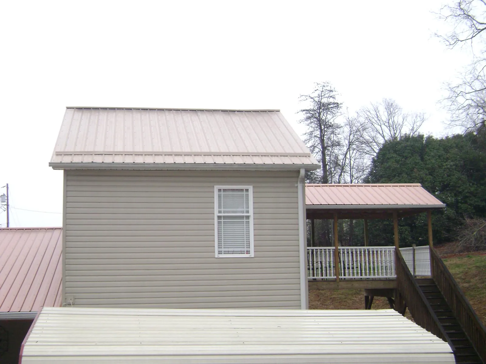 Tan metal roofs on a two story addition and attached porch, from a Roof Replacement job in Zanesville